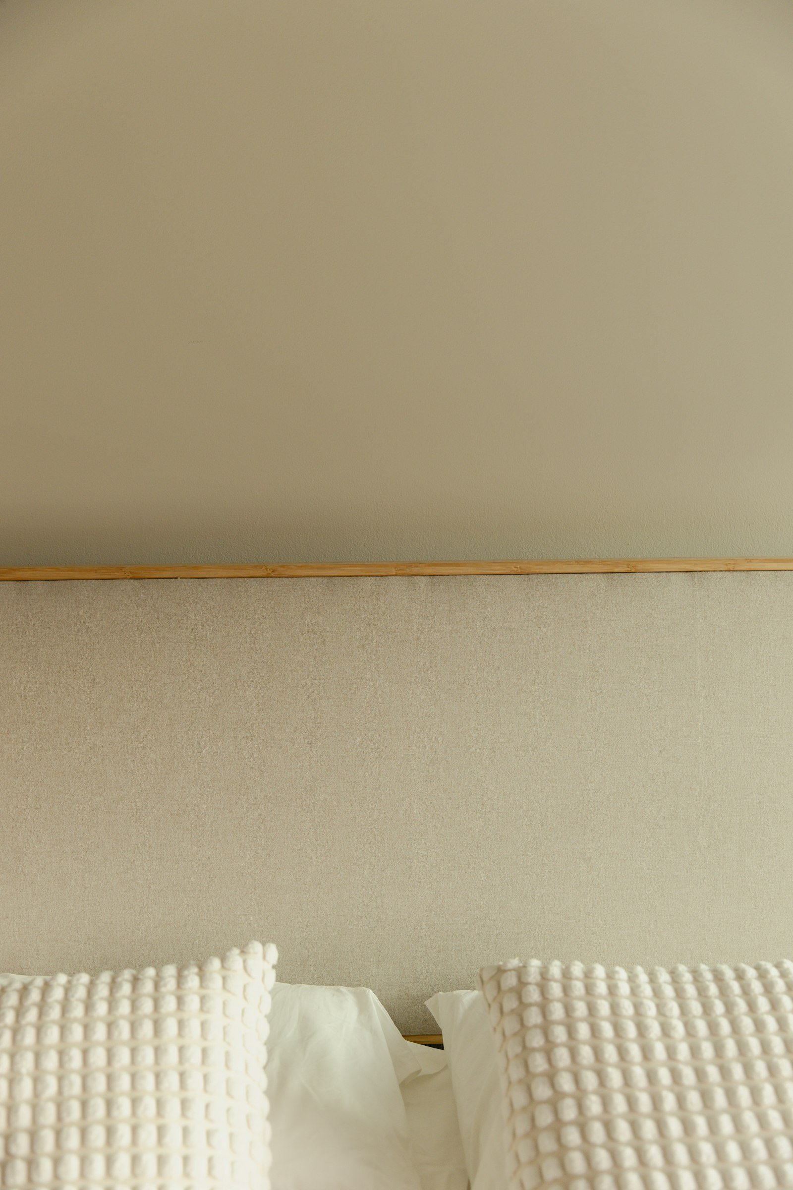 Quarto aconchegante em tons de bege, com cama e cabeceira estofada