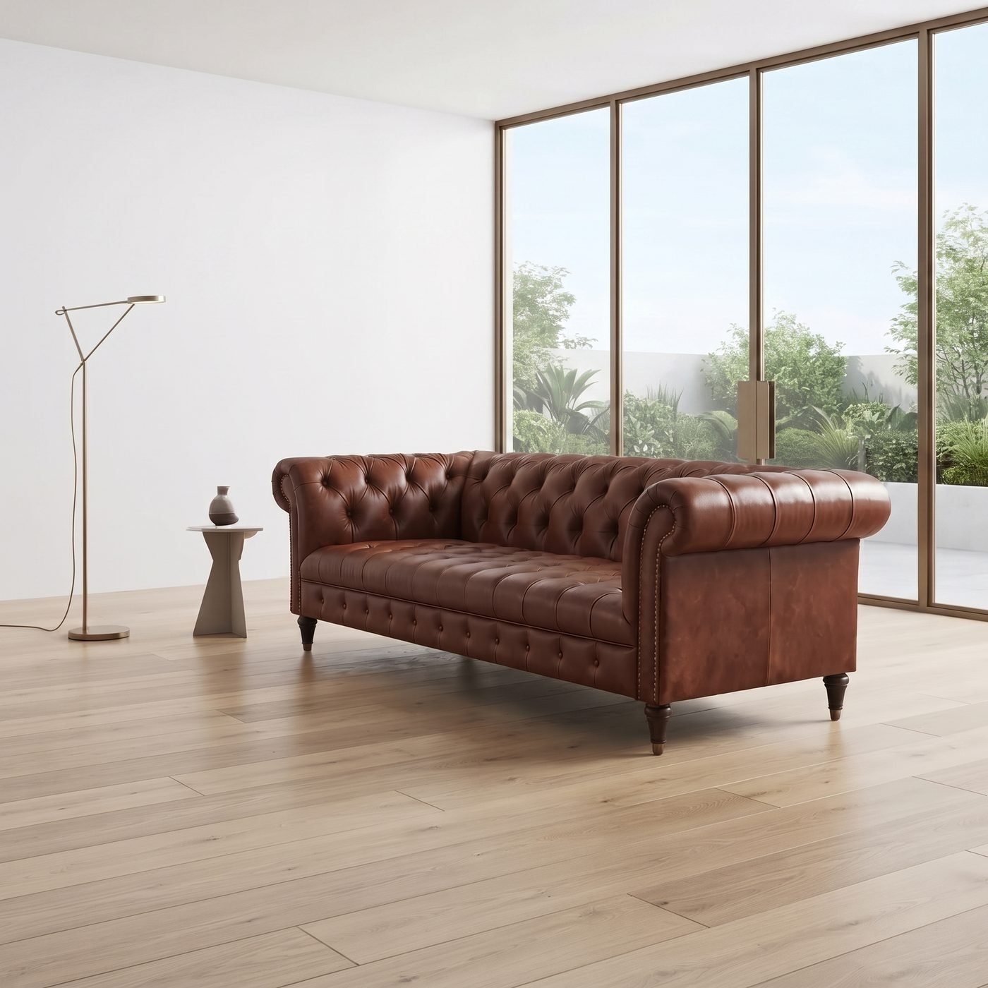 Sala ampla de paredes brancas e janelões, com sofá Chesterfield capitonê de couro caramelo, piso claro, luminária de piso e mesa lateral