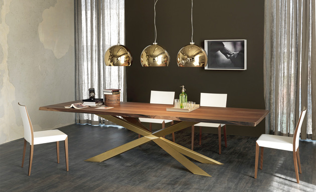 Mesa Spyder com base dourada e cadeiras brancas numa sala de jantar de parede escura