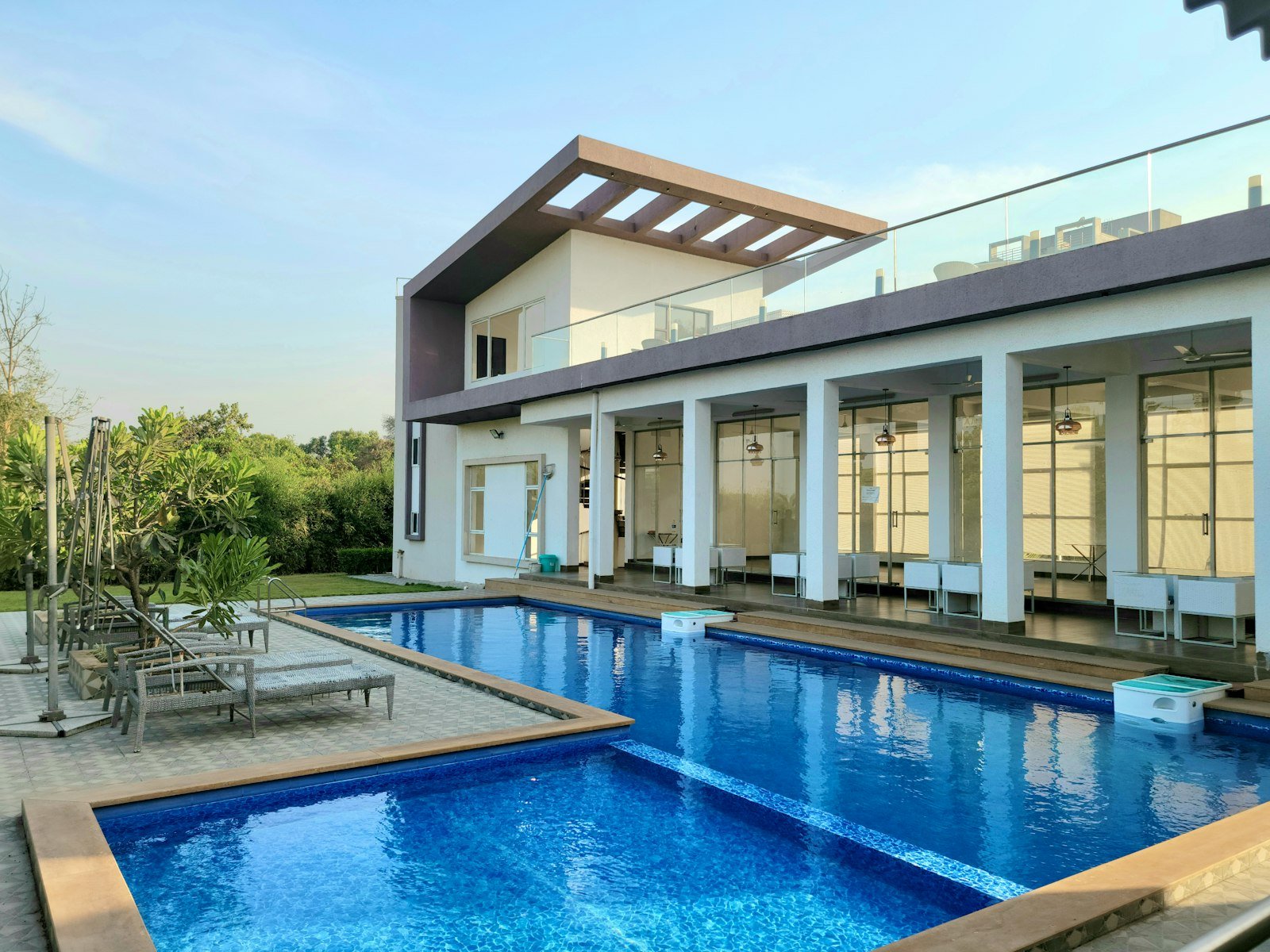 Piscina tropical diante de uma casa com vegetação ao redor