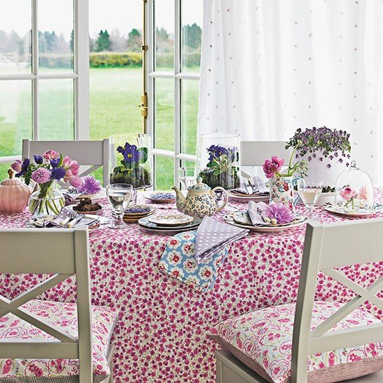 Mesa com toalha florida e cadeiras almofadadas