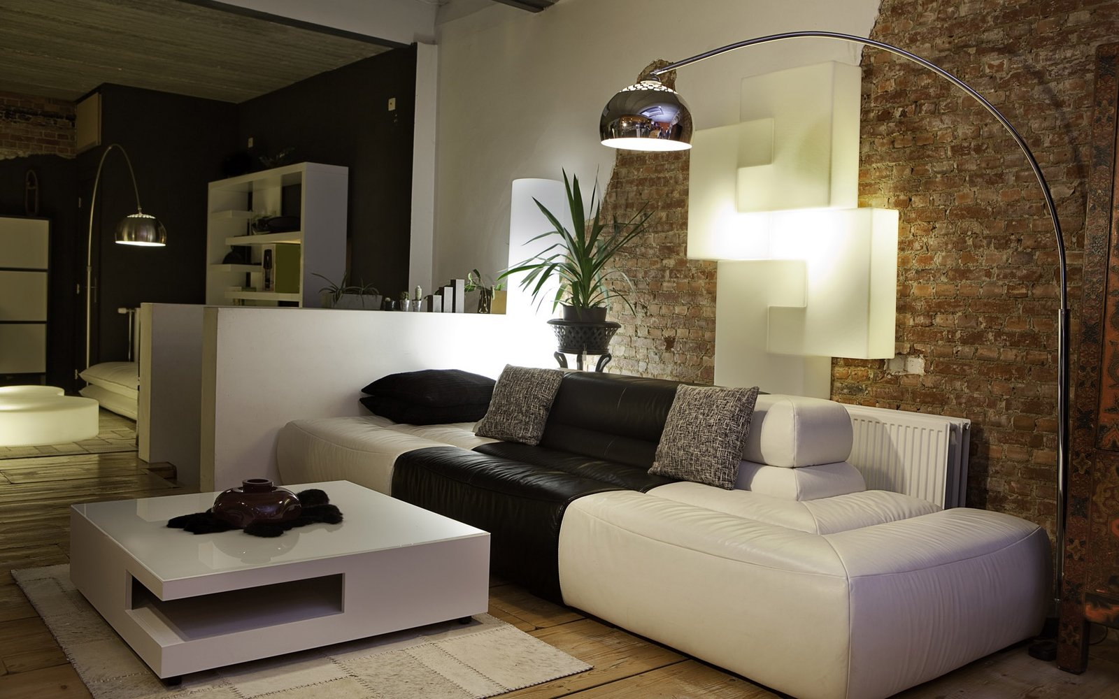 Sala com sofá e mesa de centro de formato redondo, diante de uma parede de tijolos aparentes