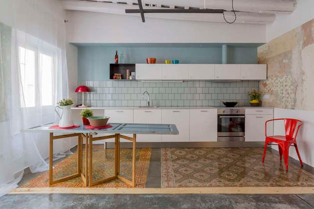Apartamento compacto com piso de concreto e um tapete de ladrilho estampado marcando um ambiente