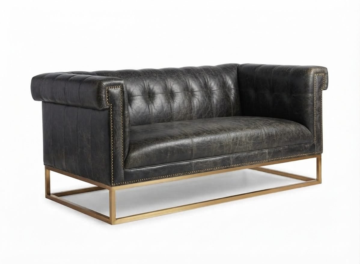 Estofado Hungria em couro grafite envelhecido com capitonê e base em metal dourado, vista de três quartos em fundo branco.